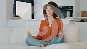 African woman calm lady with curly hair biracial girl sit cross-legged on sofa in lotus position closed eyes do