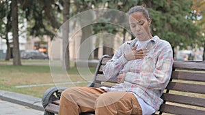 African Woman Coughing while Sitting on Bench Outdoor