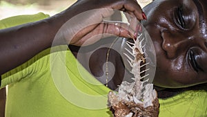 African woman eating fish.