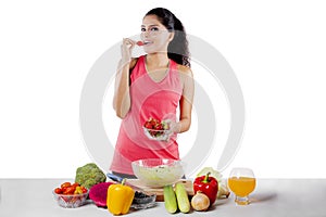 African woman eating fresh strawberry on studio