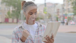 African Woman Excited for Success on Tablet Outdoor