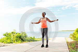 African woman exercising with jump rope on beach