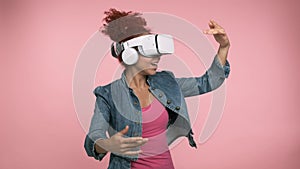 African woman experiencing virtual reality with VR glasses. Watching virtual reality 3d video isolated on pink