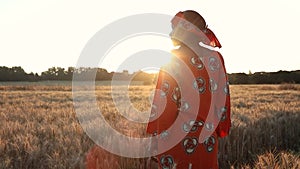 African woman farmer in traditional clothes standing in a field of crops in Africa at sunset or sunrise