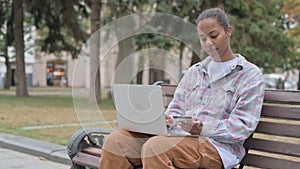 African Woman Frustrated by Online Shopping Failure, Sitting Outdoor on Bench