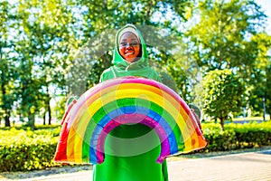 african woman in green hijab with bright makeup with rainbow air balloon in summer park outdoor photo