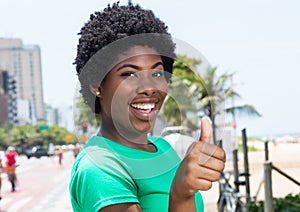 African woman in a green shirt in the city showing thumb