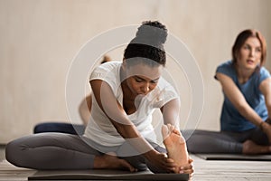 African woman and group of people in Janu Sirsasana pose