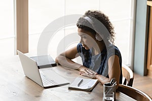 African woman in headset ponder on information at pc screen