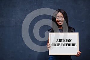 African woman hold white board with Abidjan Cote d`Ivoire inscription. Most populous city in Africa concept