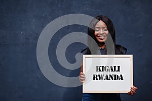 African woman hold white board with Kigali Rwanda inscription. Most populous city in Africa concept