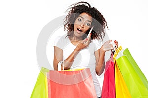 African woman holding shopping bags talking by phone.