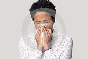 African woman holding tissue blowing running nose studio shot