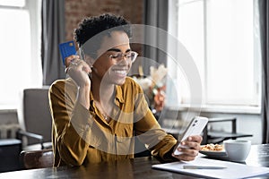 African woman holds credit card use smartphone do online shopping