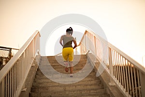 African woman jogging on the stairs. View from bac