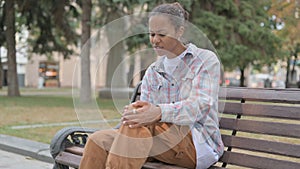 African Woman with Knee Injury Sitting on Bench Outdoor