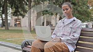 African Woman with Laptop Looking at Camera while Sitting Outdoor on Bench