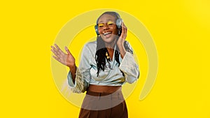 African Woman Listening Music In Earphones Singing Over Yellow Background