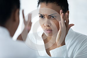 African woman looking in mirror see mimic wrinkles feels stressed