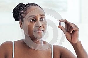 African woman looking at a pill in her hand