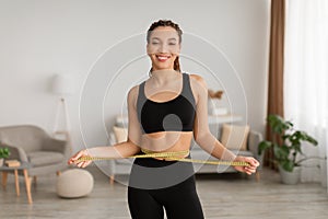 African Woman Measuring Waist With Tape Showing Weight Loss Indoor