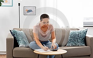 African woman with papers and calculator at home