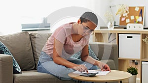 African woman with papers and calculator at home