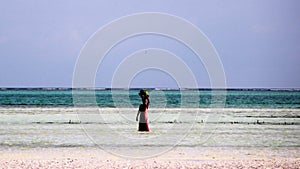 African woman in pink with a basket on her head