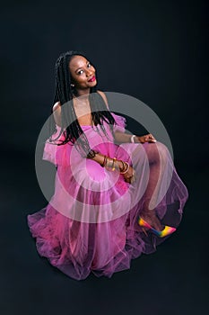 African woman in a pink dress on a black background