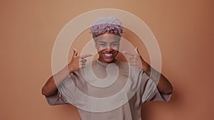 African woman pointing with fingers to healthy white teeth and broad smile