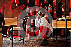 African woman posed against wall with old extinguisher.