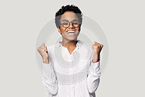 African woman raised hands clenched fists feels happy studio shot