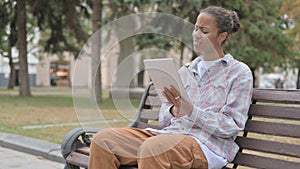 African Woman Reacting to Loss on Tablet while Sitting Outdoor on Bench