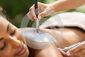 African woman receiving mud spa treatment