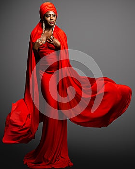 African Woman in Red Dress and Silk Headscarf. Fashion Black Skin Lady in Muslim Abaya Hijab and Golden Earrings over Dark Gray.