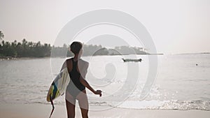 African woman running with surfboard in ocean water. Black female surfer with surf board. Pretty multiethnic girl goes