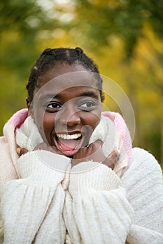 African woman screaming and covering up with a scarf in autumn.