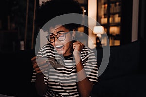 African woman screaming with joy while playing game on mobile phone