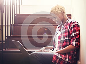 African Woman Searching Internet Sitting on Steps photo