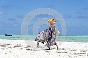 African woman sell souvenirs and clothes for tourist near the ocean on the sand beach in Zanzibar island, Tanzania, Africa