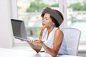 African woman sending kiss to laptop computer