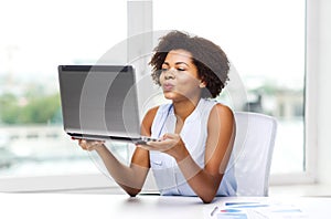 African woman sending kiss to laptop computer