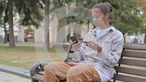 African Woman Shopping Online while Sitting Outdoor on Bench
