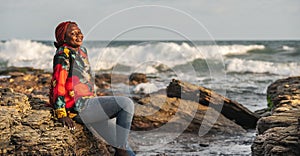 African woman sitting on the beach cliffs at sunset