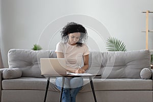 African woman sitting at coffee table holding pen writing