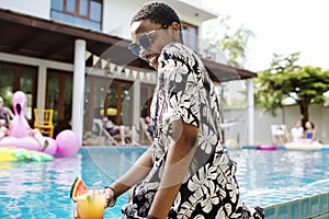 African woman sitting by the pool enjoying summer time