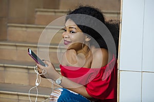 African woman sitting on stairs listening to music