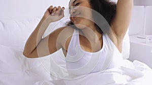 African woman with sleeping mask in bed at home