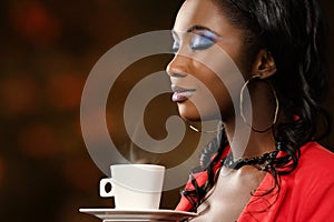 African woman smelling coffee with eyes closed.