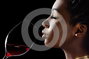 African woman smelling red wine aroma.